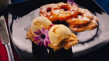 Een nagerechtbord met geglazuurde donuts en ijs, inclusief een mes en lepel.