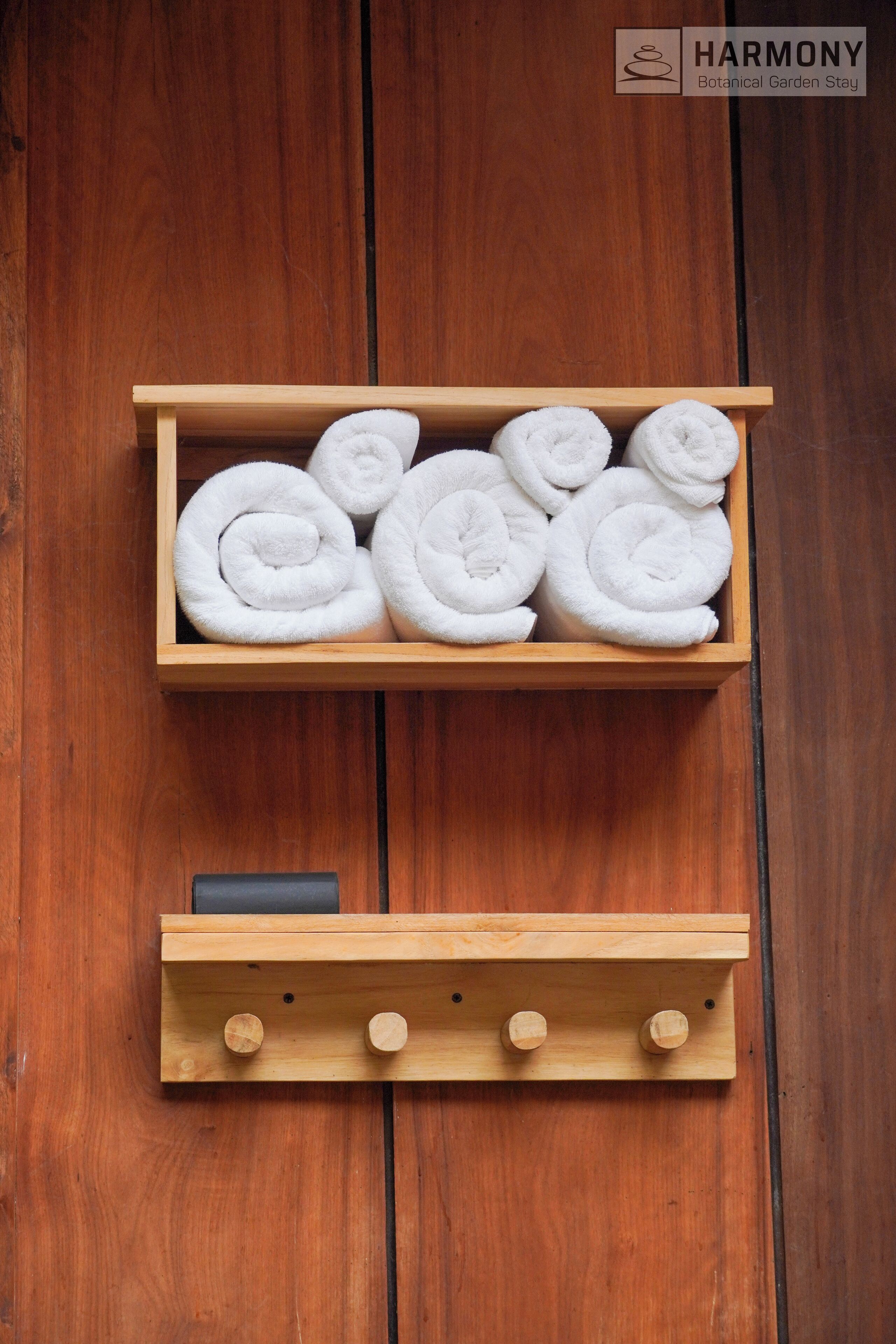 A wooden shelf with neatly rolled white towels and a smaller shelf below it.