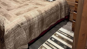 Una stanza accogliente e piccola, con pareti in legno e un letto con copriletto e cuscini a motivi.