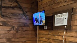 Un interno in legno con un grande tavolo in legno e panche, una televisione montata a parete e un condizionatore d'aria bianco.
