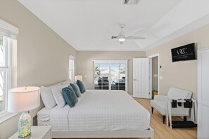 Une chambre à coucher avec un lit, une chaise, une lampe et un ventilateur de plafond.