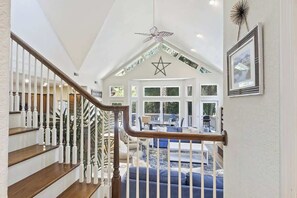 A spacious interior with a staircase, a large living area with a blue sofa, and a star-shaped ceiling ornament. - Hidden Sea Pines Gem | Pool, Spa, Pet Friendly (Hilton Head Island)