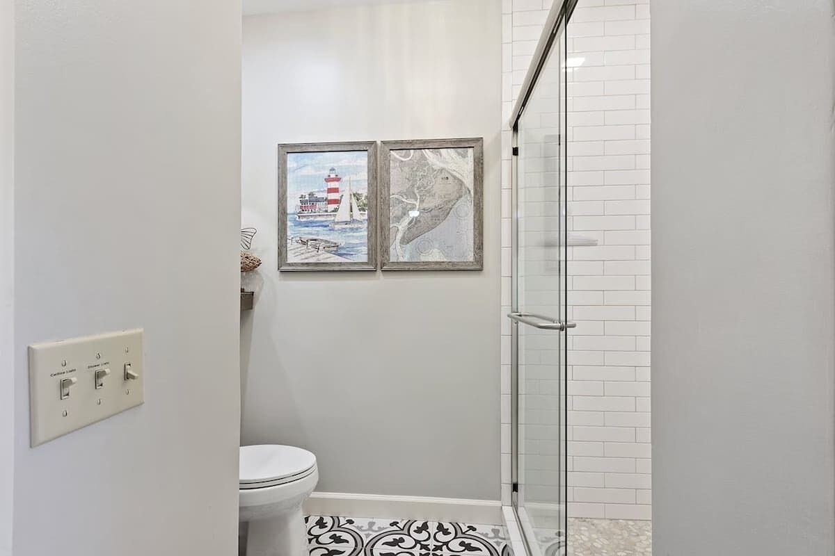 Un bagno con un water, una doccia e due quadri appesi al muro.