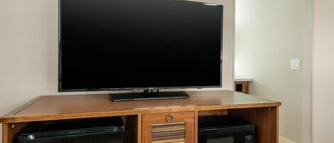 Un mueble de entretenimiento de madera con un televisor de pantalla plana, un mini refrigerador Haier y un microondas.