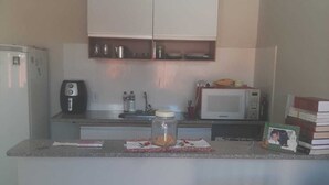 A compact kitchen with white cabinets, a microwave, a toaster, and a small refrigerator. - Charming 1-bedroom apartment in Armação dos Búzios perfect for relaxing (Armação dos Búzios)