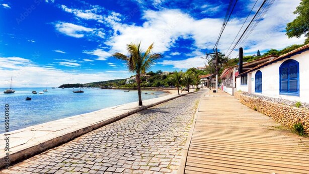 A coastal walkway with cobblestone pavement, wooden boardwalk, and buildings with blue shutters. - Charming 1-bedroom apartment in Armação dos Búzios perfect for relaxing (Armação dos Búzios)