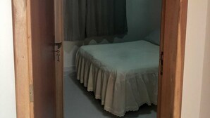 A bedroom with a bed, a window with curtains, and a door. - Charming 1-bedroom apartment in Armação dos Búzios perfect for relaxing (Armação dos Búzios)