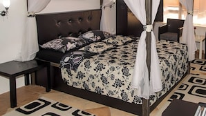 A four-poster bed with a floral bedspread, a dark headboard, and a wall-mounted artwork. - Apart Hotel Solaris: Deluxe Apartment 4: 30 m2 (Skopje)
