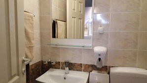 A bathroom with a white sink, a mirror, a towel rack, a soap dispenser, and a toilet. - Apart Hotel Solaris: Deluxe Apartment 4: 30 m2 (Skopje)