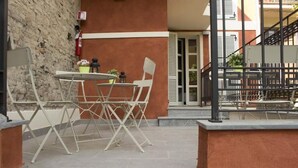 An outdoor seating area with a table and chairs, a potted plant, and a fire extinguisher on the wall. - Palazzo Domanto Parma Apartments (Parma)