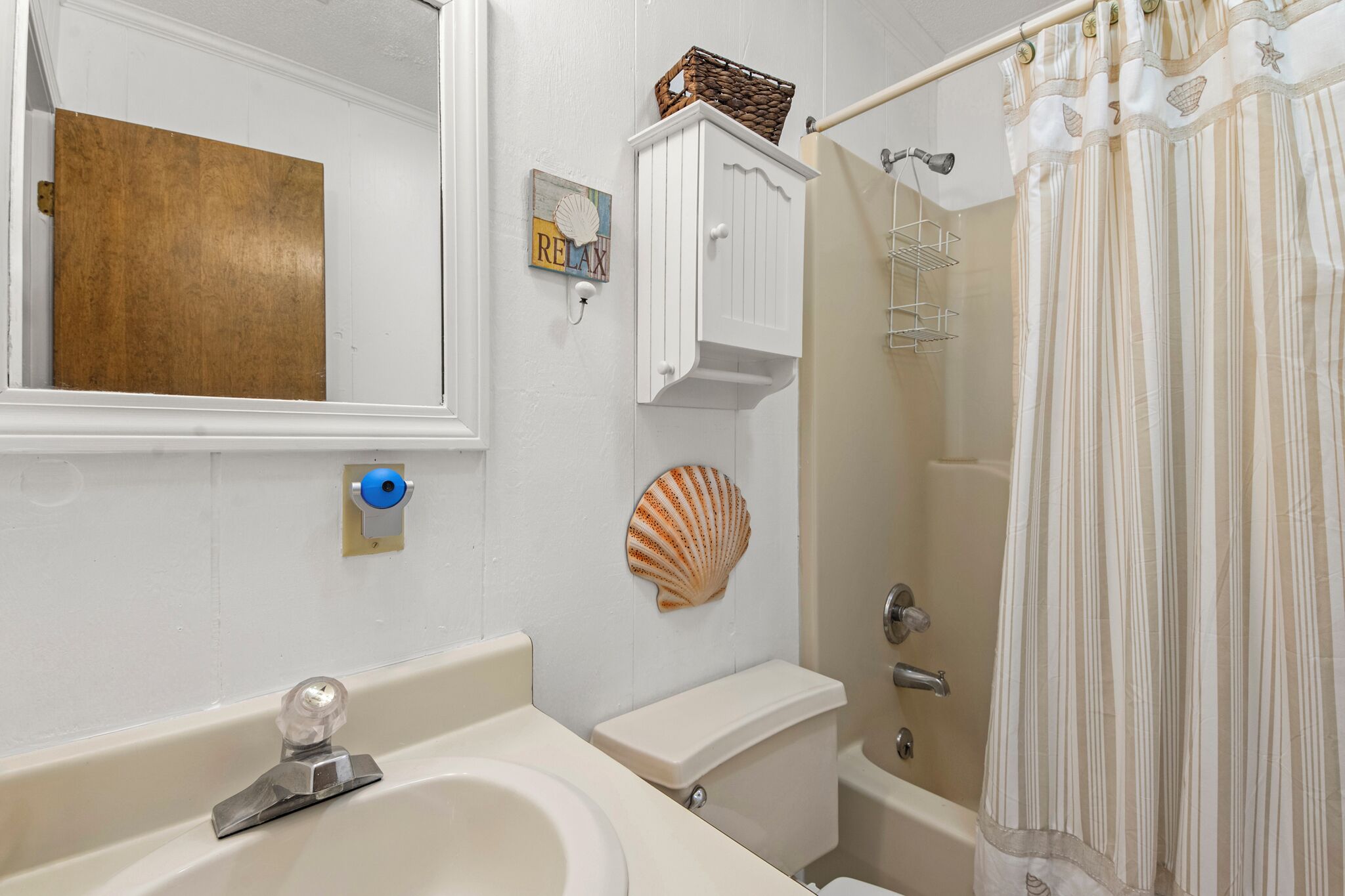 A bathroom with a white sink, a mirror, a toilet, and a shower curtain.