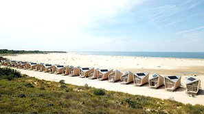 Een strand met rijen houten strandhutten.