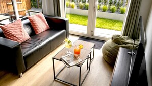 Un salon moderne avec un canapé en cuir, une table basse en verre et un magazine.
