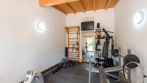 Une salle de sport équipée de matériel d’exercice, d’un tapis de course, de poids et d’un miroir.