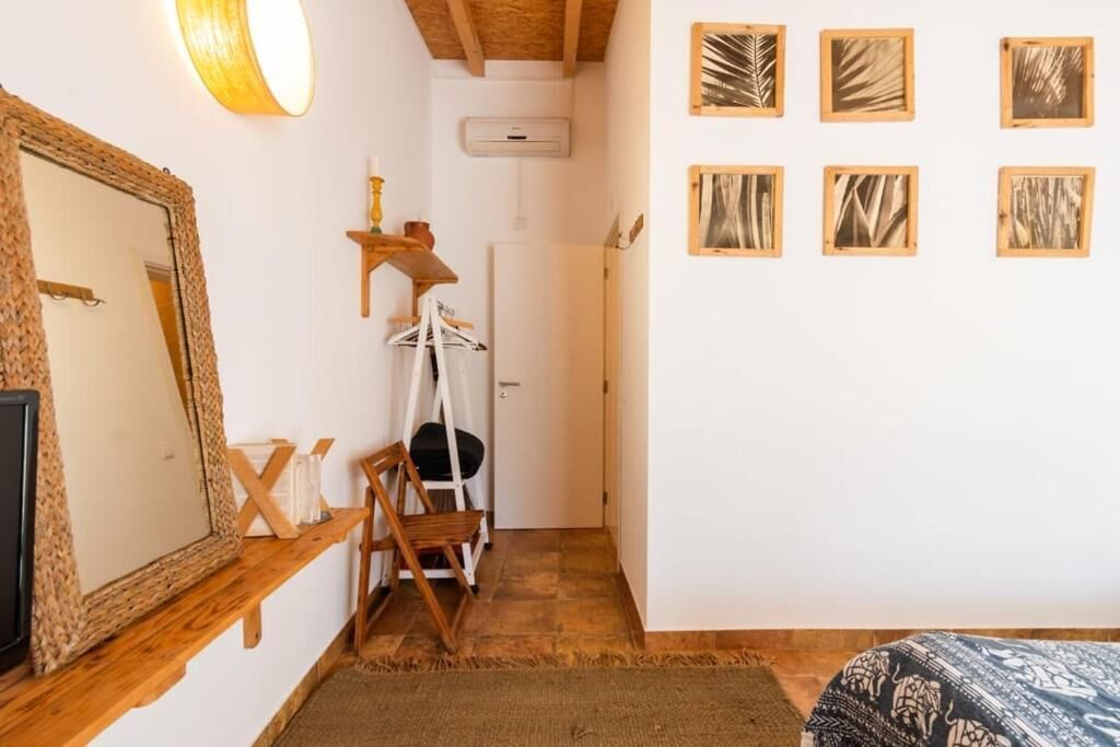 Une chambre avec un grand miroir, une étagère en bois, un fauteuil suspendu et un lit avec une literie à motifs.