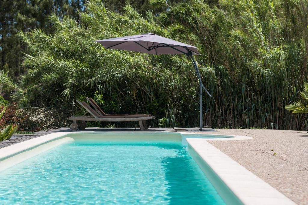 Una piscina al aire libre de temporada, sombrillas, tumbonas