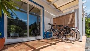Un bâtiment moderne doté de grandes portes vitrées et d’un patio où se trouvent deux vélos.