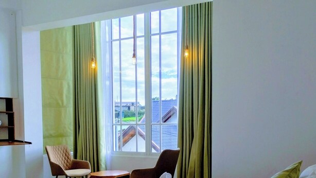 A hotel room with a large bed, a desk, two chairs, and a window with curtains. - Pensive Villa - Nuwara Eliya (Nuwara Eliya)