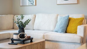 A living room with a sofa, a coffee table, and two framed artworks on the wall. - 4BR LU Getaway! 4 Min to LU • Hot Tub • Game Room (Lynchburg)
