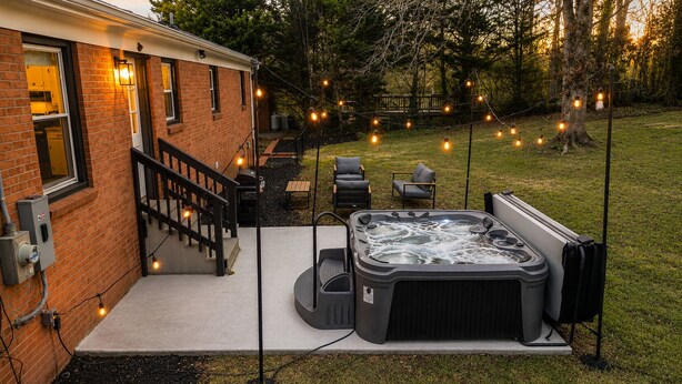 A backyard with a hot tub, outdoor seating, and string lights. - 4BR LU Getaway! 4 Min to LU • Hot Tub • Game Room (Lynchburg)
