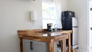 Une cuisine équipée d’un plan de travail en bois, d’un évier, d’une machine à café, d’un four à micro-ondes et d’un réfrigérateur.