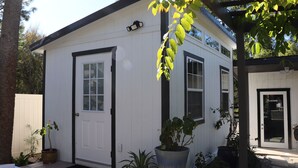 Un bâtiment blanc d’un seul étage, doté d’une porte, de fenêtres et d’un porche agrémenté de plantes en pot.