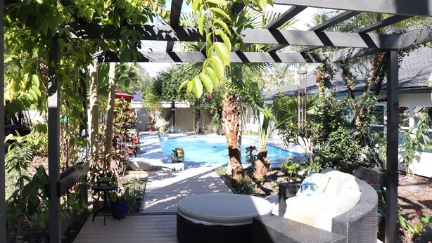 Un espace extérieur abrité comprenant une piscine, des sièges et des plantes.