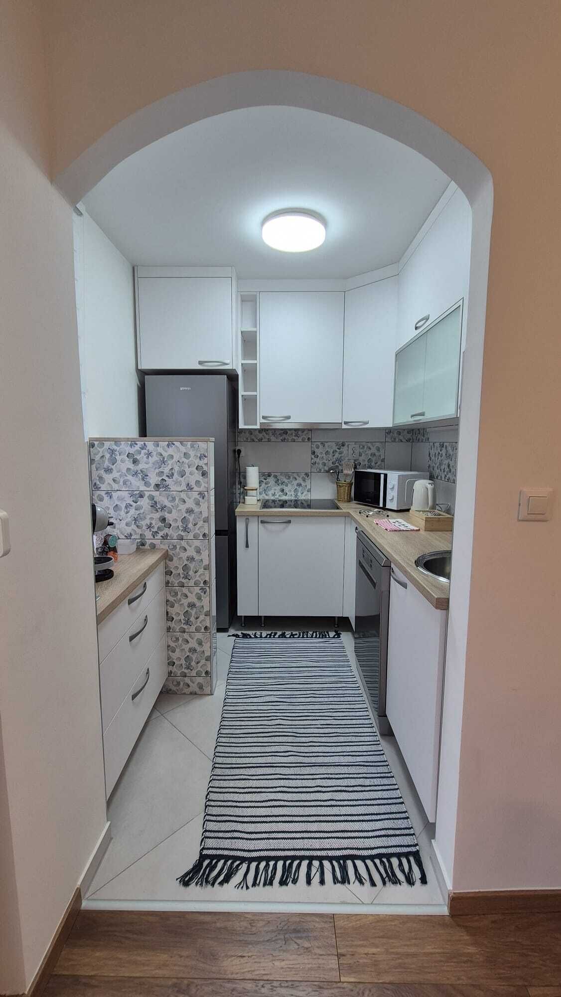 Cocina compacta con armarios blancos, microondas, refrigerador y un salpicadero con diseño.