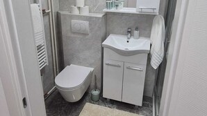 Un baño pequeño con inodoro, lavabo y zona de ducha.