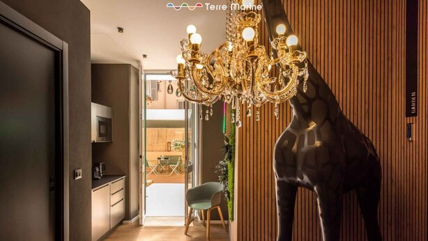 Een modern interieur met een kroonluchter, een girafbeeld en uitzicht op een eetruimte.
