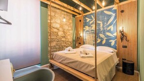 Een kamer met een bed, een hangstoel, een stenen muur en een houten wandpaneel met een bladmotief.