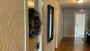 Un couloir doté d’un plancher en bois, d’un paillasson et d’une guirlande accrochée au mur.