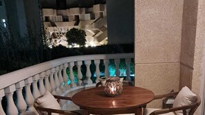 A round wooden table with two wicker chairs, each with a cushion, set on a tiled patio.