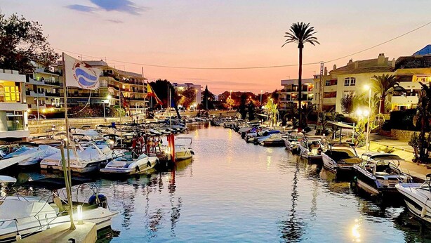 A marina at dusk with boats docked along the water.