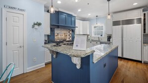 Eine moderne Küche mit blauen Schränken, Granit-Arbeitsplatten und Pendelleuchten.