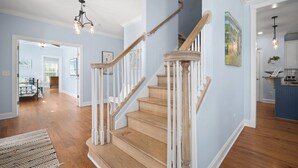Eine Treppe mit Holzdielen und weißen Geländern, die zu einem Essbereich mit Tisch und Stühlen führt.