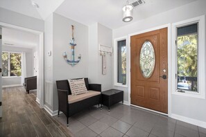 A hallway with a wooden door, a black wicker bench, and a wall-mounted anchor decoration. - Peaceful Marsh-Side Escape, Golf Cart Included, Pets Considered - 936 Stone Crab (Fripp Island)