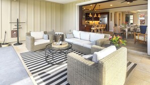 A spacious living area with wicker furniture, a black and white striped rug, and a ceiling fan. - Blue Lani at Holua Kai (Kailua-Kona)