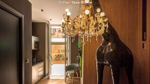 Een modern interieur met een kroonluchter, een girafbeeld en uitzicht op een eetruimte.