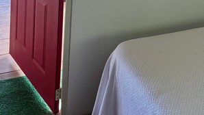 Uma porta vermelha com uma janela, um mapa do México e dois espelhos com moldura preta em uma parede branca.
