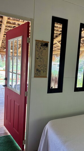 Eine rote Tür mit Fenster, eine Mexiko-Karte und zwei spiegelnde Wände in schwarzen Rahmen an einer weißen Wand.