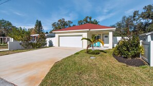 A single-story house with a red roof, a garage, and a well-maintained lawn. - Cozy Spacious New Build • 10 minutes to Beaches (Largo)