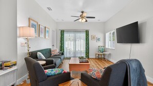 A living room with a sofa, armchairs, a coffee table, a TV, and a ceiling fan. - Cozy Spacious New Build • 10 minutes to Beaches (Largo)