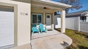 A residential house with a garage, a covered porch with two chairs, and a number '1114' on the wall. - Cozy Spacious New Build • 10 minutes to Beaches (Largo)