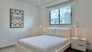 A modern bedroom with a bed, nightstands, and a window with a city view. - *Classy*wifi-A/C-Gym-BlueMall-YellowKey (Santo Domingo)