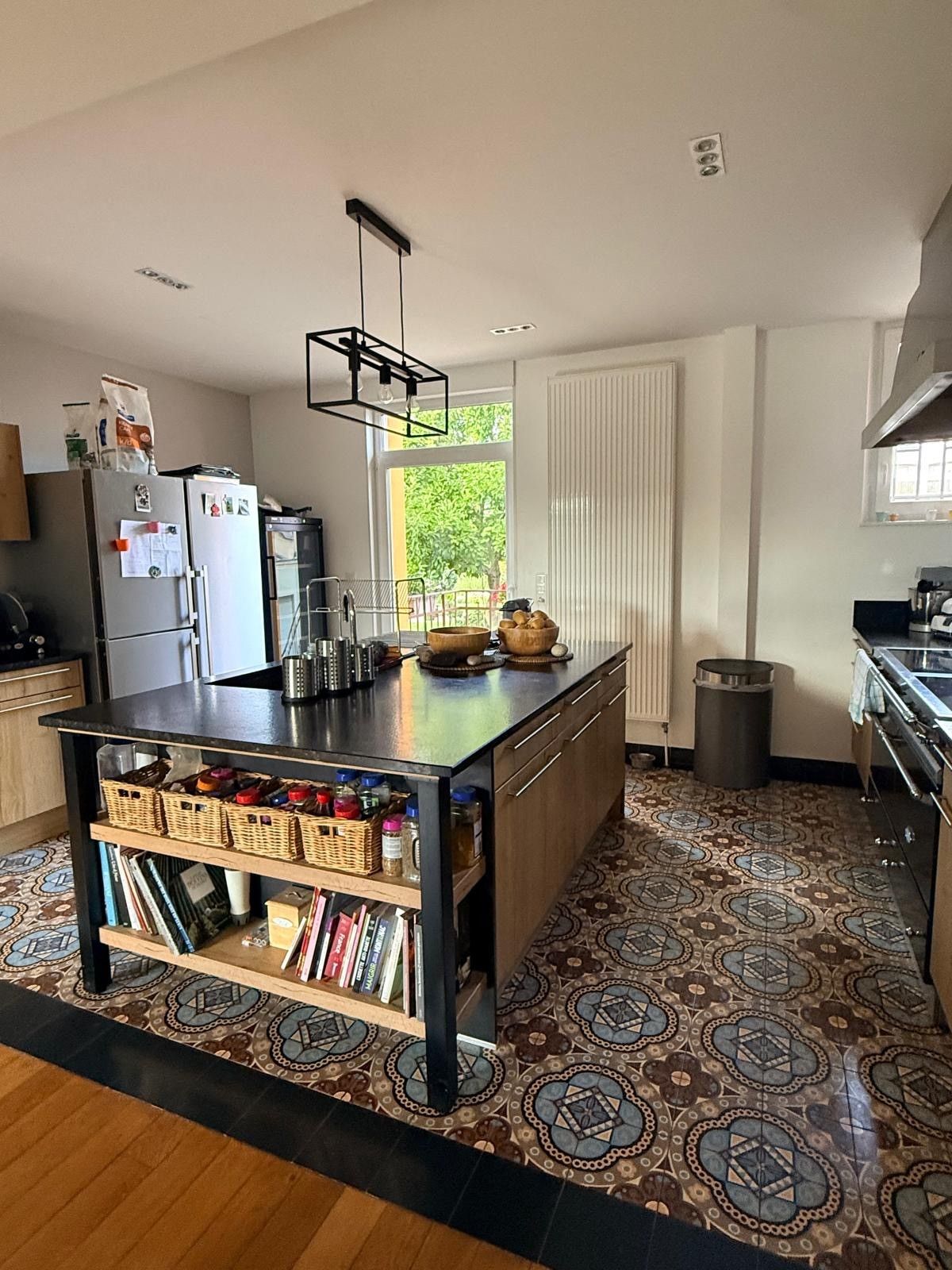 Een moderne keuken met een centraal eiland, een ingebouwde boekenkast en een vloer met een patroon.