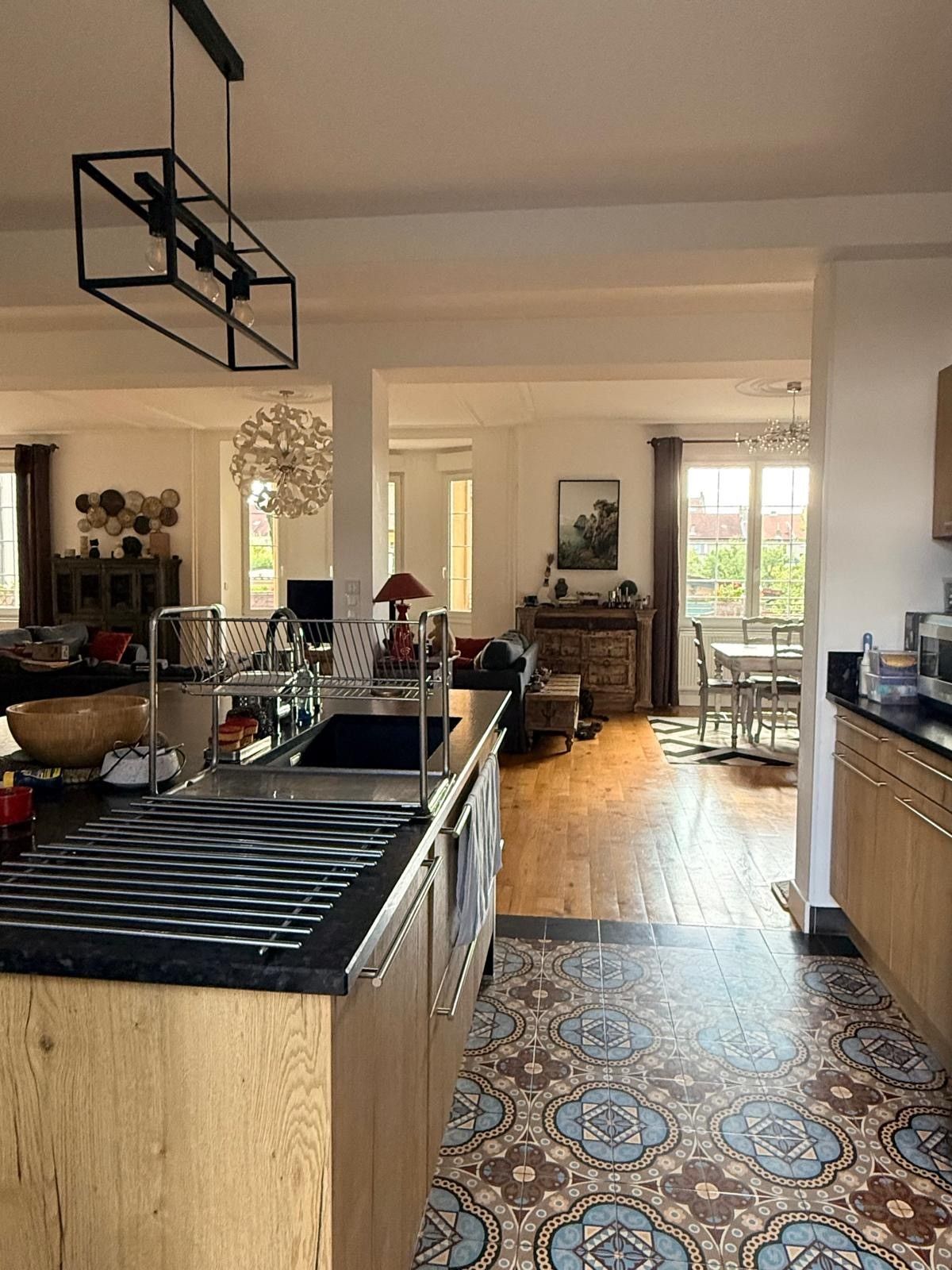 Een ruime keuken met een centraal eiland, houten vloeren en een eethoek met een tafel en stoelen.