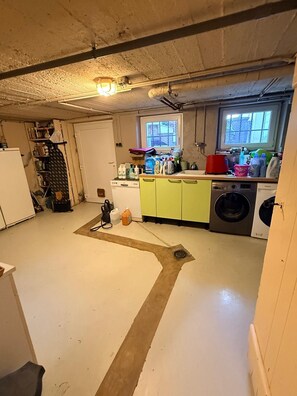Eine kompakte Küche mit Waschmaschine, Kühlschrank und einem Fenster, das für natürliches Licht sorgt.