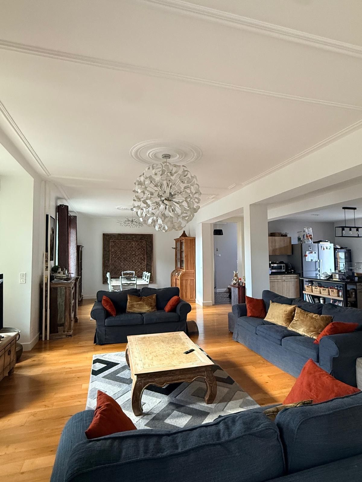 A spacious living room with two sofas, a coffee table, and a modern chandelier.