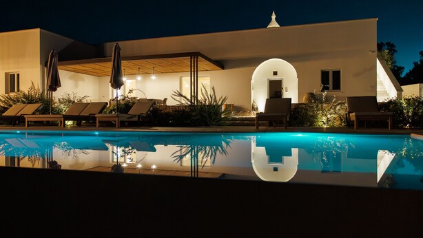 A modern building with a swimming pool, lounge chairs, and a covered patio area. - Villa Ninetta Ostuni (Ostuni)